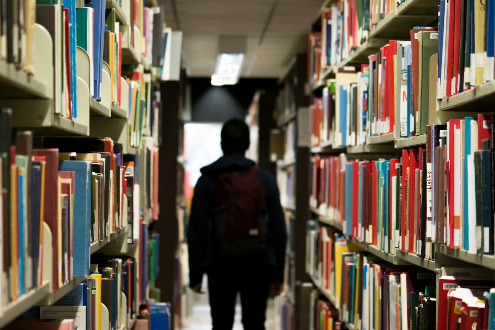 A person walking between tall library shelves
